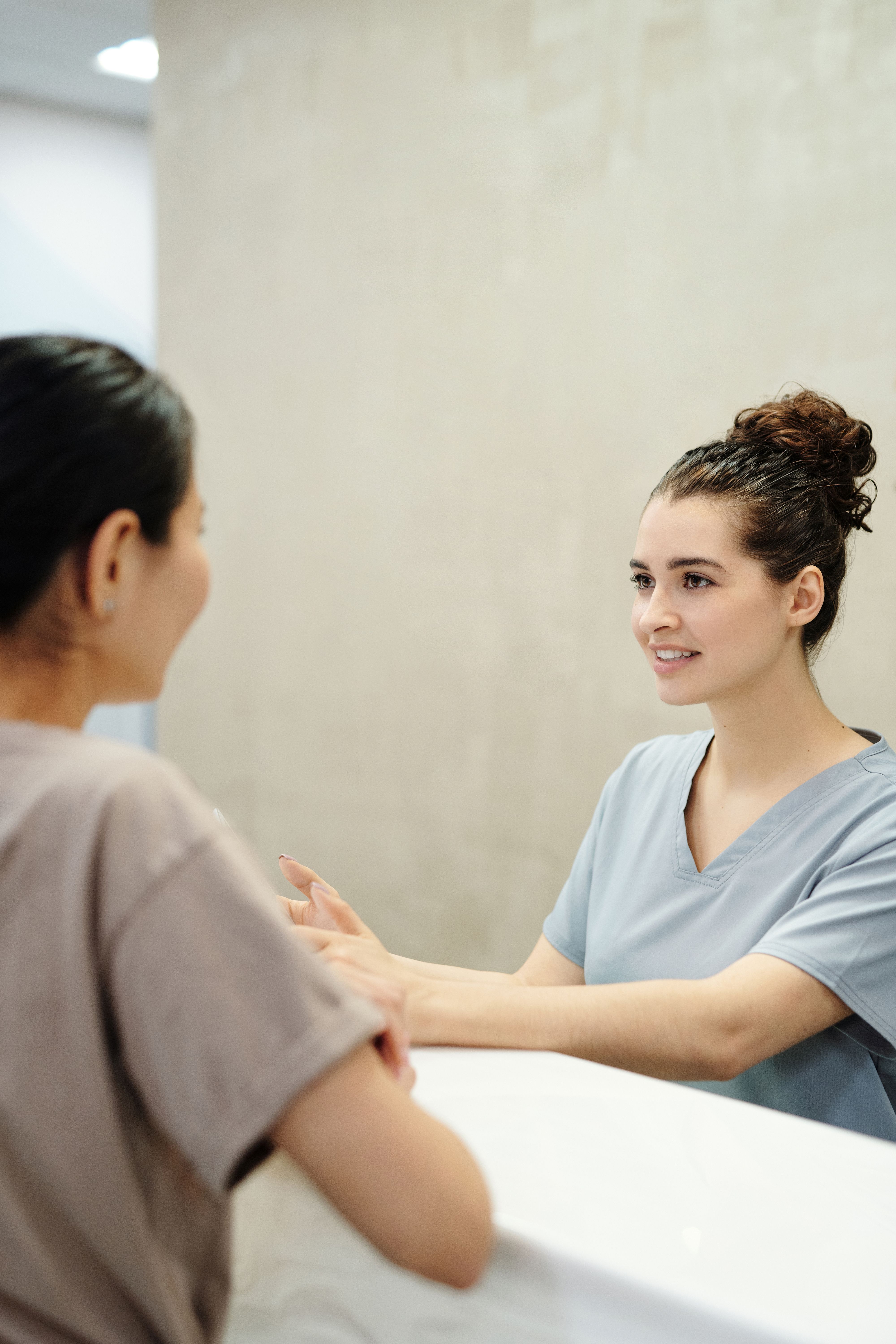 A healthcare professional speaking with a colleague at a reception desk